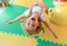 Enjoyable time. Top view of a happy cute girl while lying on the fitness ball