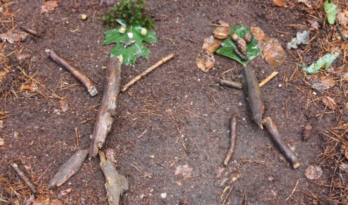 Takken op de grond gelegd in de vorm van twee poppetjes