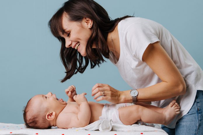 Pedagogisch medewerker verschoont lachende baby voor schone luier