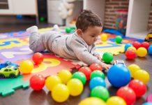 Baby kruipt op de grond tussen gekleurde speelgoedballen