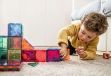 Jongetje speelt op de grond met magenetische bouwstenen op kinderopvang