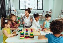 Kinderen en een leraar zitten aan tafel en spelen met speelgoed.